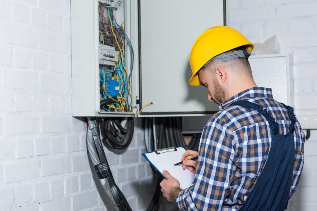 Electricista profesional inspeccionando el cableado de un cuadro